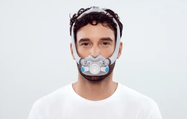 Close-up of a man wearing the AirTouch F30i CPAP mask, demonstrating the top-of-head hose connection.