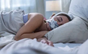 Woman sleeping peacefully on her side with the ResMed AirTouch F30i mask.
